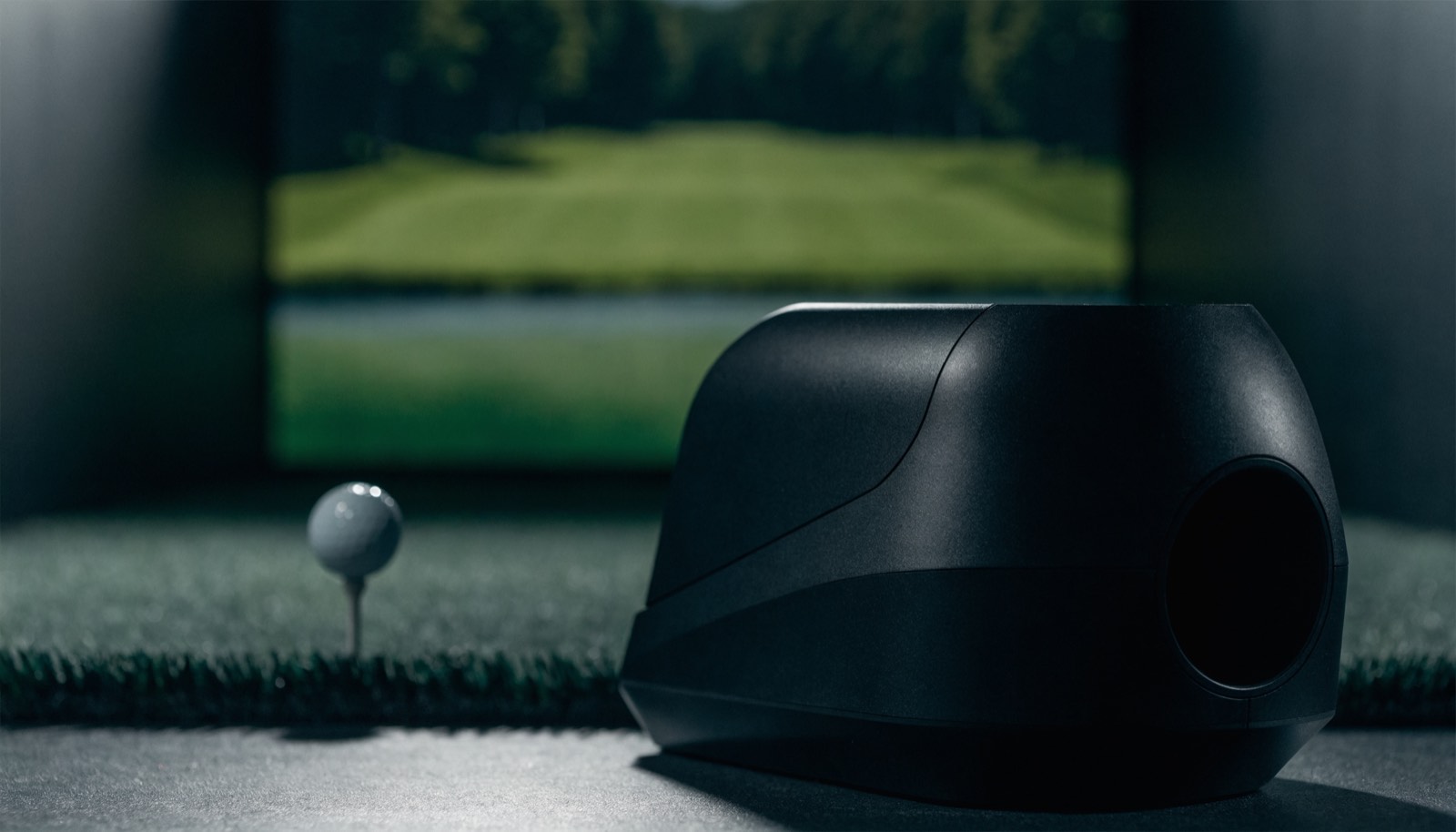A launch monitor beside a teed ball on an indoor hitting mat