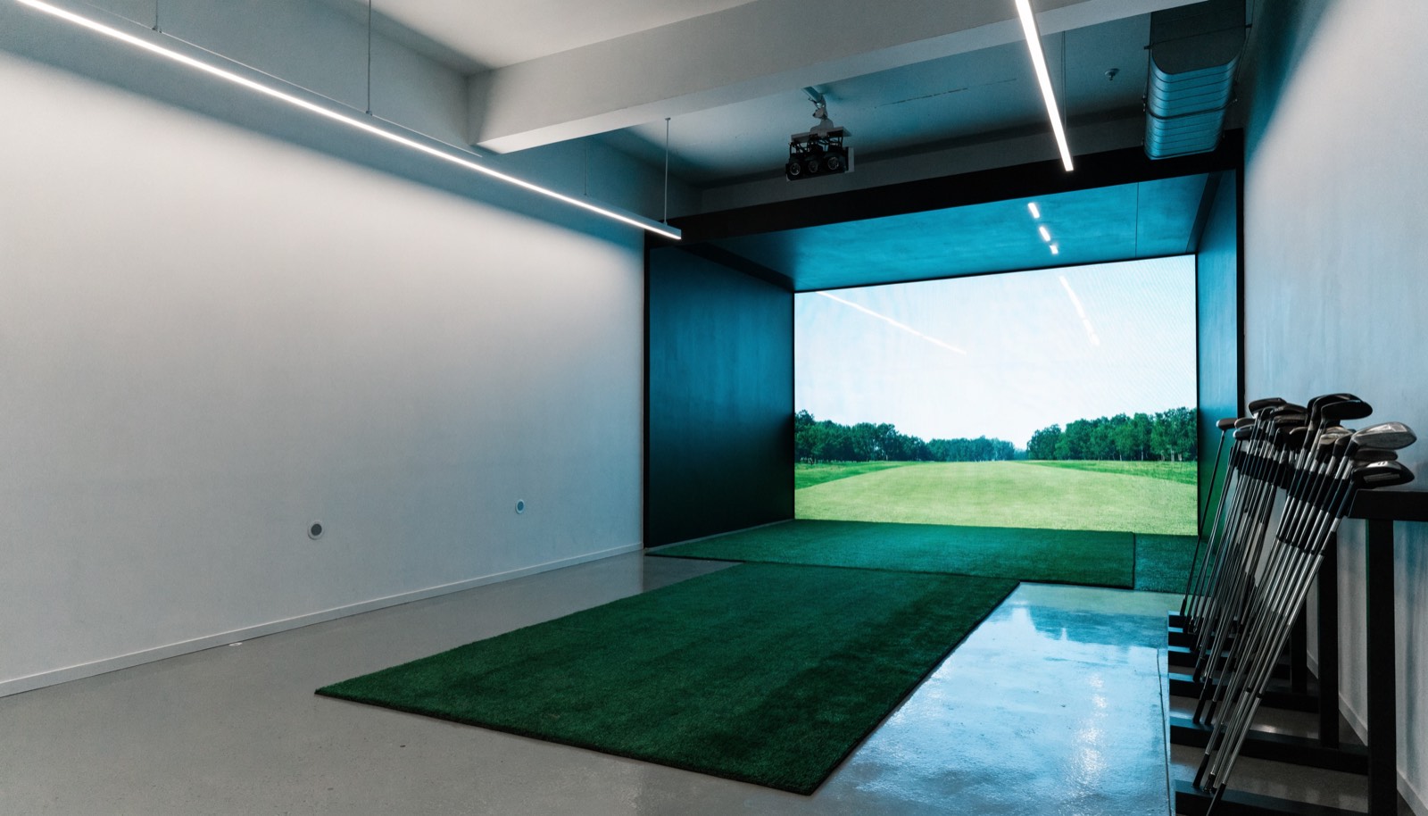 A clean indoor practice bay with a club rack and overhead camera